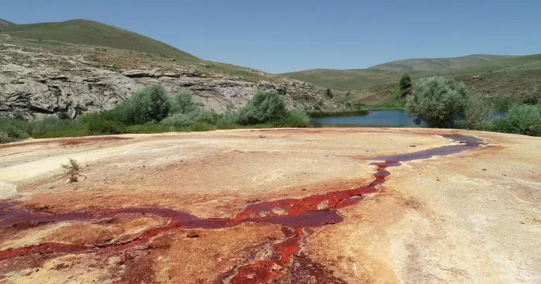 Lac roșiatic și drum săpat în stâncă, între pereți de 500 m